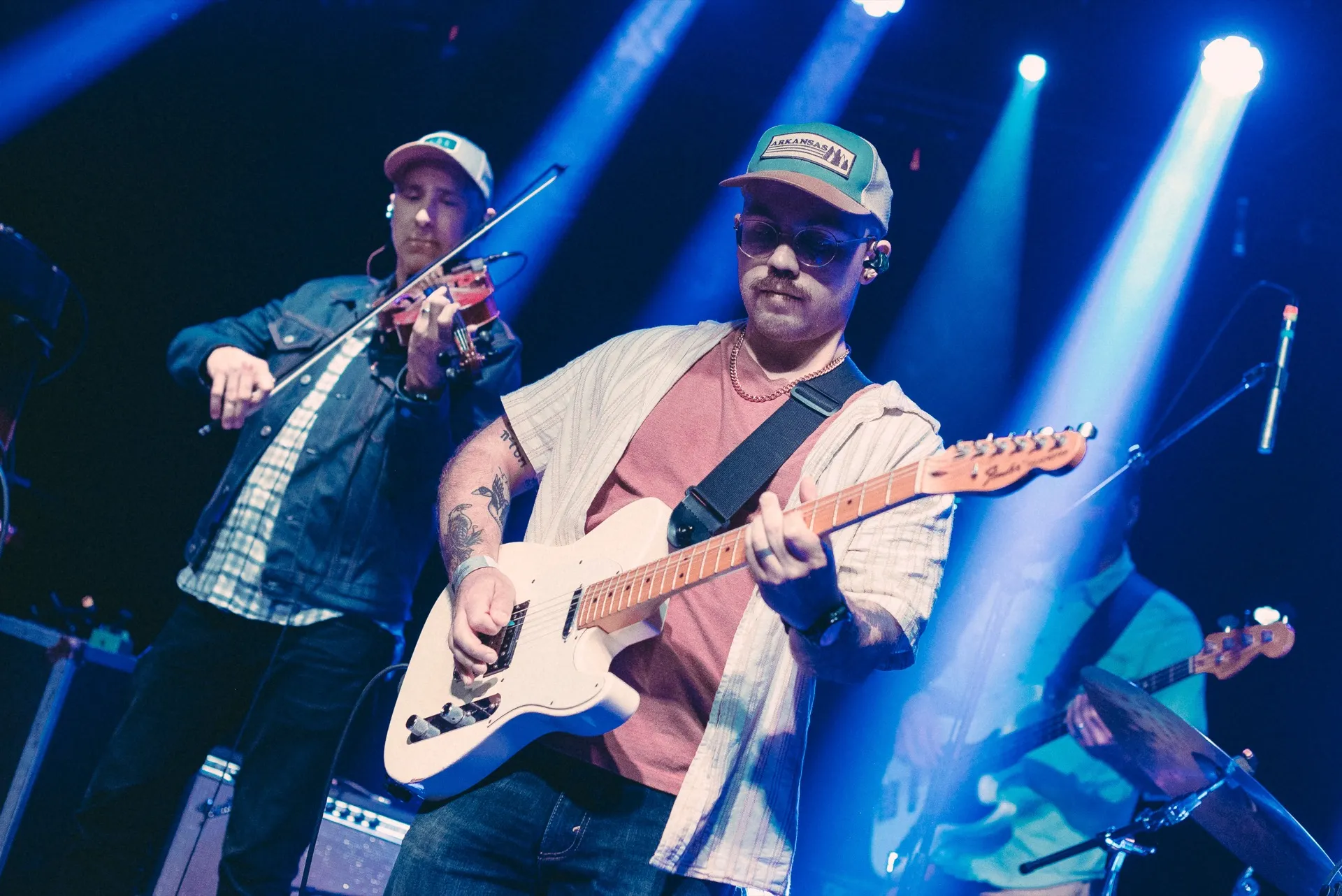 Big Holler performing live — guitar and fiddle under blue stage light